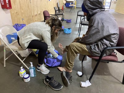 KCU student helps houseless person by providing foot care. 